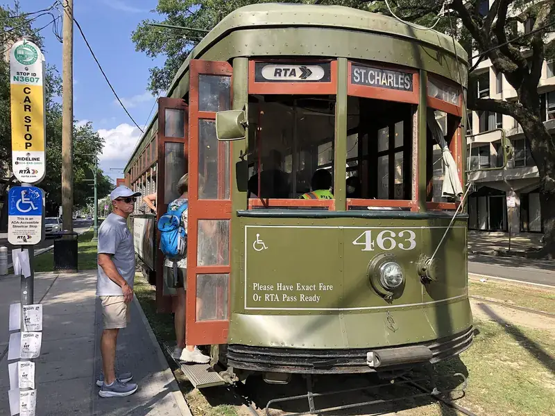 A green St. Charles streetcar stopped at a corner in the Garden District of New Orleans